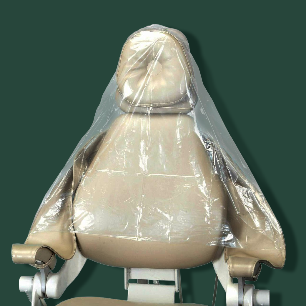 A beige dental or medical examination chair covered with a clear plastic sheet, shown against a dark green background.